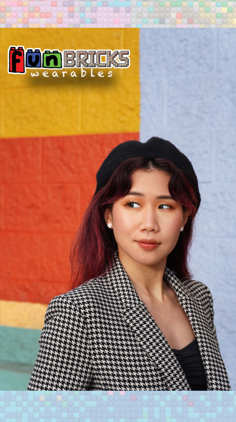 Woman wearing black, white, and grey LEGO earrings standing in front of a colorful wall.