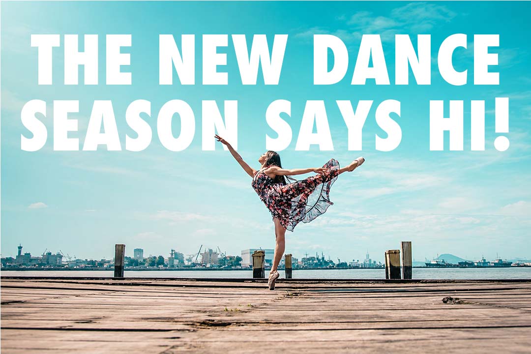 Ballet dancer posing on a waterfront boardwalk beneath a bright blue sky with the title "The New Dance Season Says Hi!"