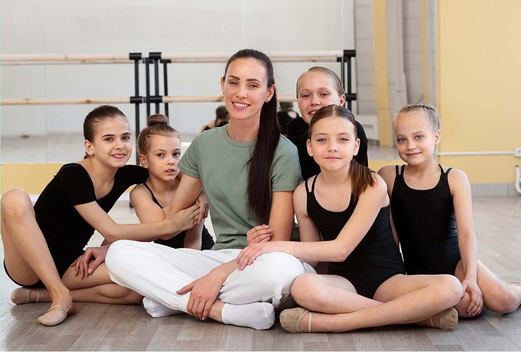 Dance Studio Goals for Dancers and Teachers Dance teacher sitting with a group of young dancers inside a dance studio